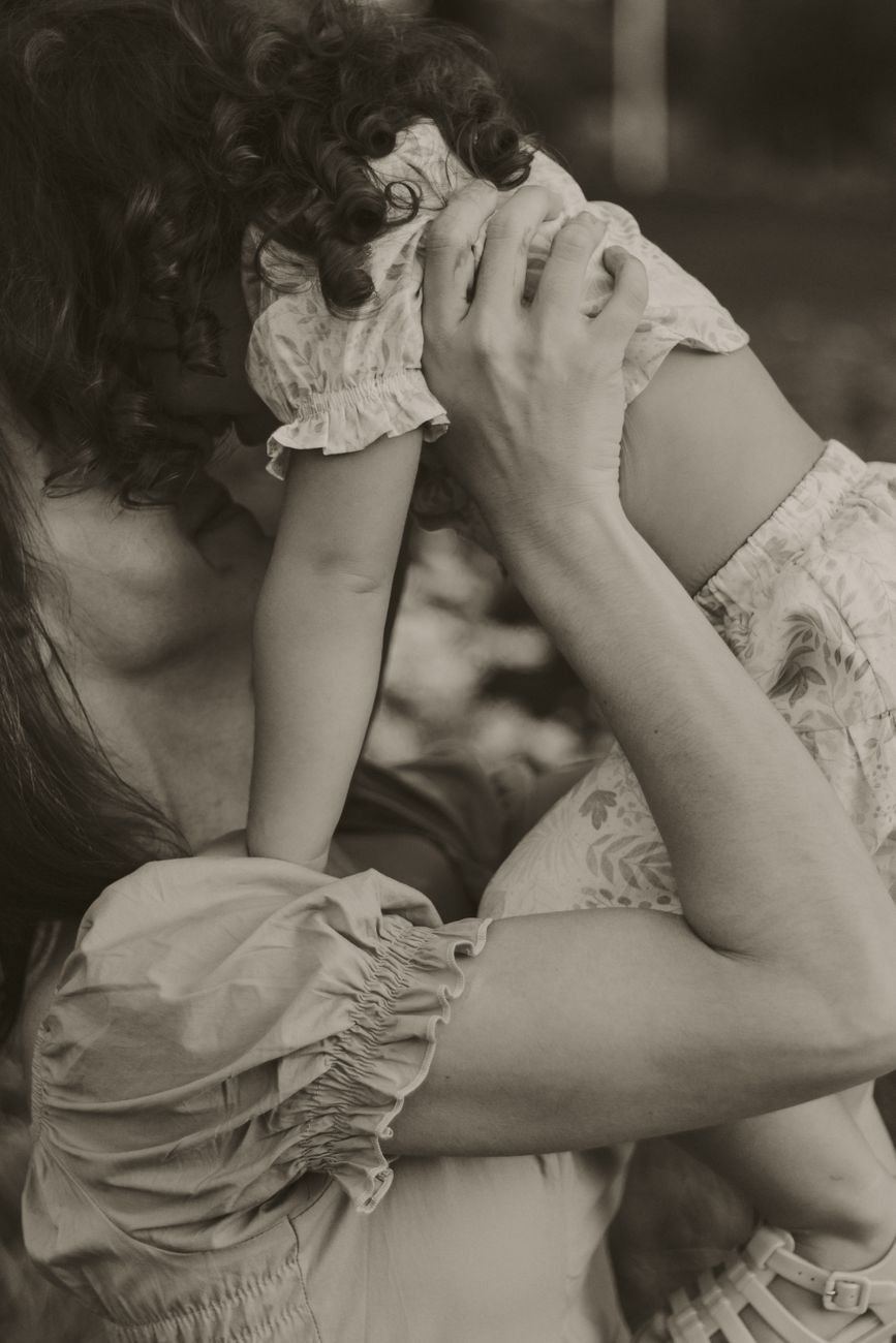 A tender moment of a mother holding her child close outdoors.